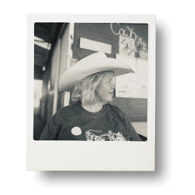 Black-and-white portrait of Danielle wearing a cowboy hat, looking down with soft light.
