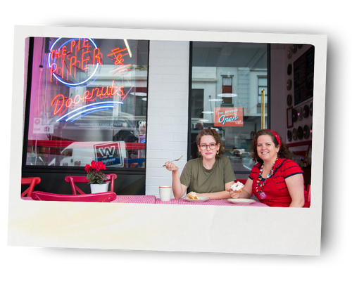Danielle Butler and her daughter Suzanne sitting outside their bakery and café, The Pie Piper on Karangahape Road in Auckland, enjoying fresh desserts at the outdoor table.